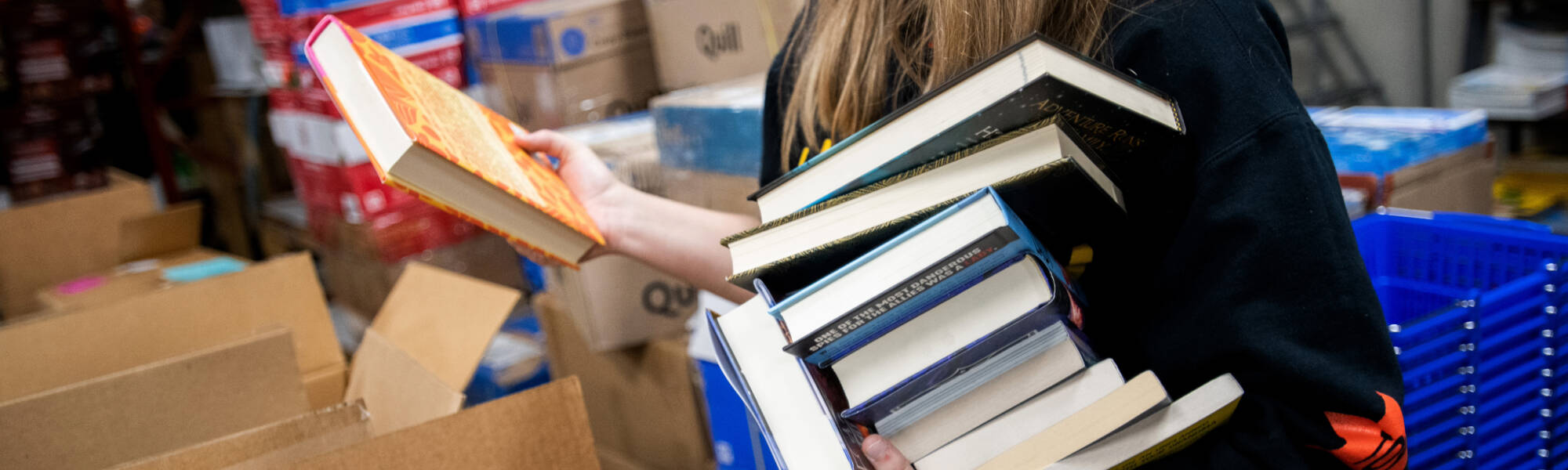 A person holding a stack of textbooks.